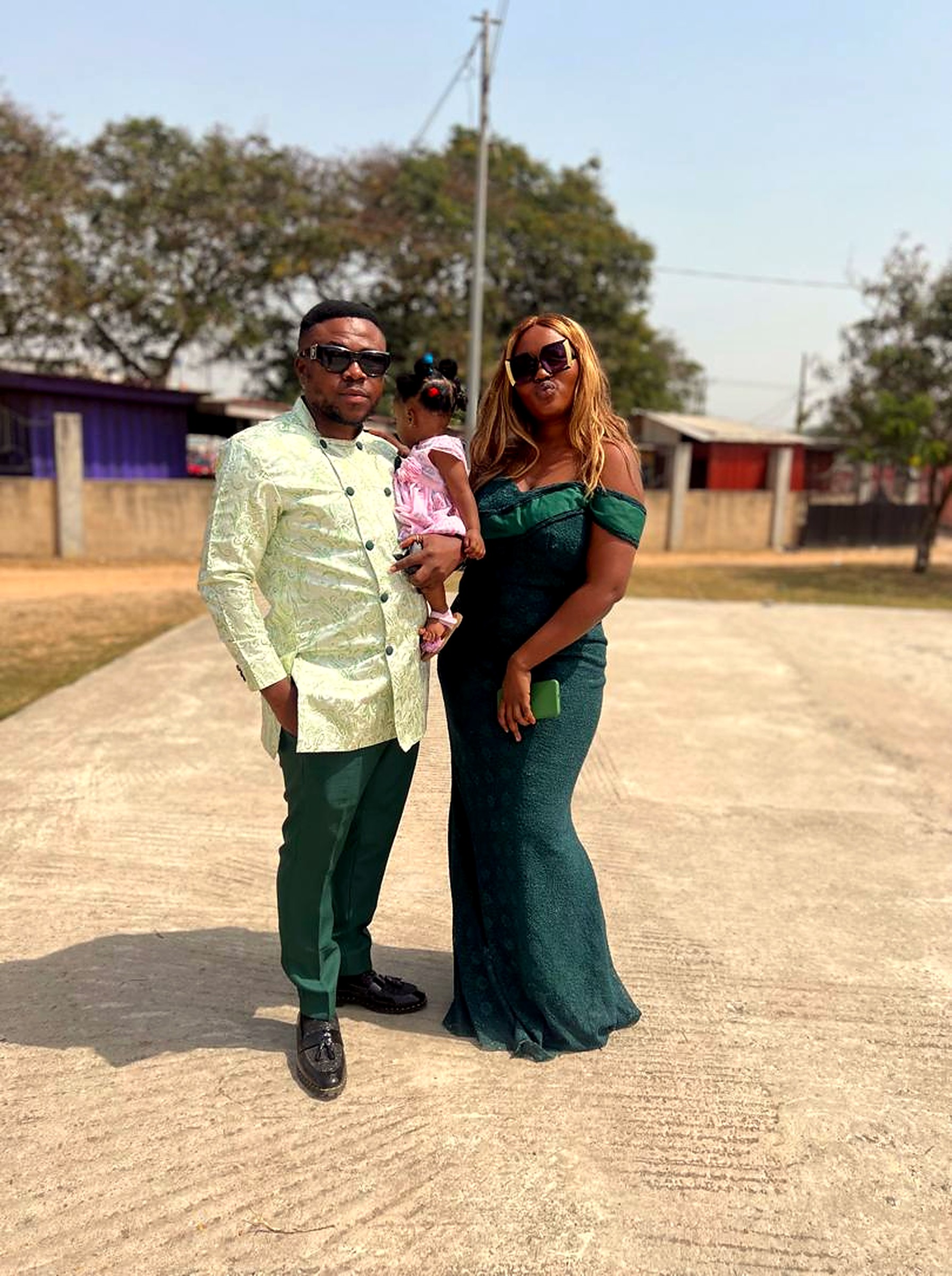 Eddy and Kessewa in emerald green, holding their little one
